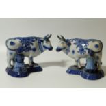 A pair of early 19thC Dutch Delft blue and white milkmaid and cow groups, each with standing cow