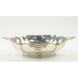 A white metal twin handled oval dish, possibly American, with embossed foliate decoration, stamped