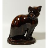 A 19thC treacle glazed pottery figure, of a standing cat, in black and yellow on a shaped base (