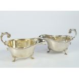 A pair of George VI silver sauce boats, with flying scroll handles and three shell stepped feet.