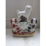 A 19thC Staffordshire clock group, the circular dial surmounted by poodle and flanked by two
