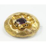 A Victorian memorial brooch, set with a garnet, hair filled memorial window verso in yellow metal.