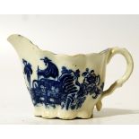 An 18thC blue and white porcelain cream jug, the shaped body with upper flowing rim and ear