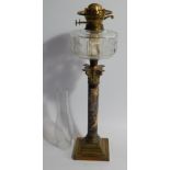 An Edwardian table oil lamp, with faceted clear glass reservoir, Corinthian column stem with marbled