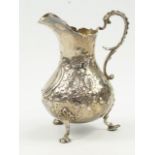 A Victorian silver cream jug, of baluster form with embossed floral decoration, shield reserve,