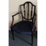 A mahogany open arm chair in Sheraton style, the shield shape back with reeded rails carved with