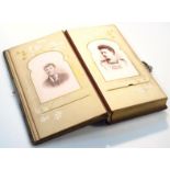 A Victorian photograph album, with pressed leather black boards raised with a floral pattern,