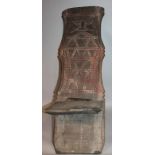 An African tribal panel or seat, the inverted back heavily carved with a facial expression above a