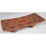 A 20thC African carved hardwood tribal head rest, the rectangular canted top set with a geometric