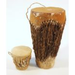 A 20thC African tribal drum, formed with animal hide top and textured tapering body on circular foot
