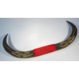 A pair of faux horns, with material centre carved with buildings and trees, unmarked, 75cm wide.