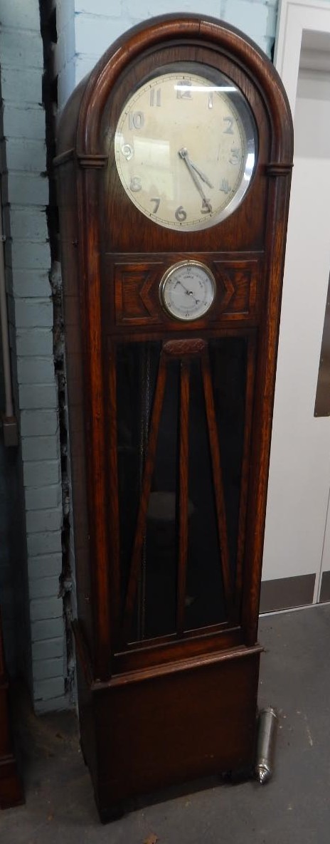 An early-mid 20thC oak longcase timepiece, the circular silvered dial above a aneroid barometer, the