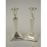 A pair of George V silver candlesticks, each with a circular sconce, a tapering rectangular