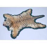 A taxidermied tiger cub skin rug, with full head, green velvet backing, 119cm long, 82cm wide.