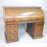 The Jim Corbett Desk, a late 19thC carved oak roll top desk, with birds eye maple veneered interior,