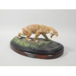 A hand painted model of a sabre tooth tiger by Carl Gage, on the oval mahogany plinth titled '