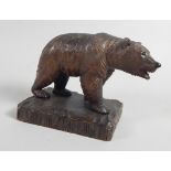 A 20thC Black Forest linden wood carving in the form of a bear, on a rectangular base, 23cm wide.