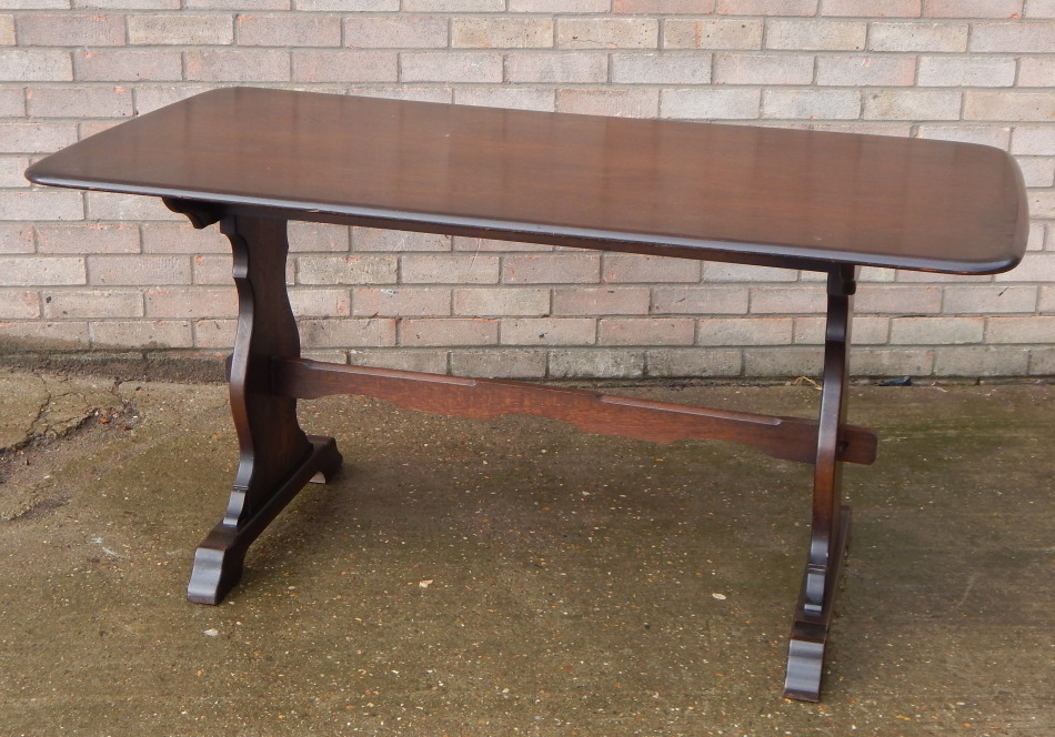 An Ercol style dark elm dining table, the rectangular top with rounded corners, and a moulded edge