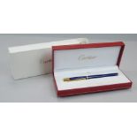 A Must De Cartier Stylo ballpoint pen, in blue with gold coloured mounts, sold with original box,