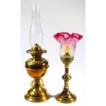 An early 20thC brass candlestick, with cranberry, clear and etched glass shade, on a cylindrical