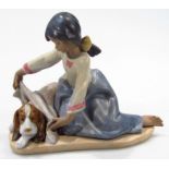 A Lladro Daisa figure, no. 2287, matt finish formed as a seated girl drying hound, printed,