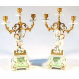 A pair of Tiche porcelain garniture vases, each with triple candle holders held on cherubic stems on