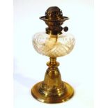 An early 20thC brass oil lamp, with clear cut glass reservoir and metal top on a leafy base