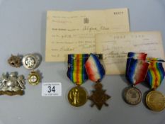 3 WWI medals, a cap badge from the Manchester regiment, 3 other badges etc.