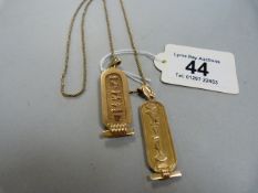 Two gold coloured Egyptian pendants (with indistinct marks) on a chain marked .750- total weight