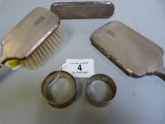 A hallmarked silver mirror and brush set and two napkin rings