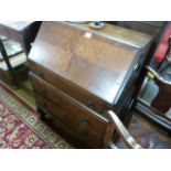 An oak bureau with three drawers under