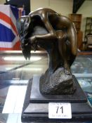 A small bronze of a lady draped on a rock