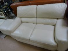 A two seater cream leather sofa and a pouffe