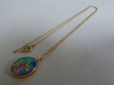 A large black opal pendant, set in gold coloured metal on an unmarked chain