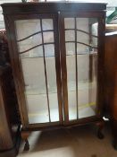 An oak bow fronted display cabinet on claw and ball feet