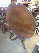 An oak tilt top breakfast table on a pedestal base