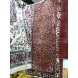 A large red ground persian runner - with an all over design