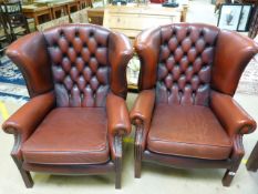 A pair of red leather button back wingback armchairs