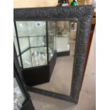 A pewter framed mirror decorated with foliage