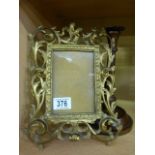 An ornate brass photo frame and an inlaid oak candlestick