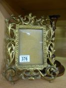 An ornate brass photo frame and an inlaid oak candlestick