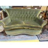 A small green upholstered button back shaped sofa
