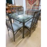 A glass topped dining table with wrought iron base and six chairs