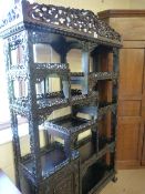 A Chinese carved darkwood side cabinet decorated throughout with carved and pierced scrolling and