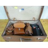 A quantity of binoculars and cameras in a vintage suitcase
