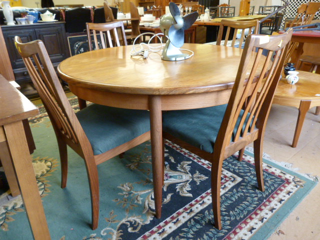 A Teak G-Plan dining table with folding extension and four teak G-Plan chairs