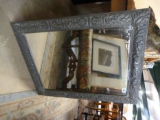 A pewter framed mirror decorated with foliage