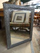 A pewter framed mirror decorated with foliage