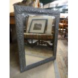 A pewter framed mirror decorated with foliage