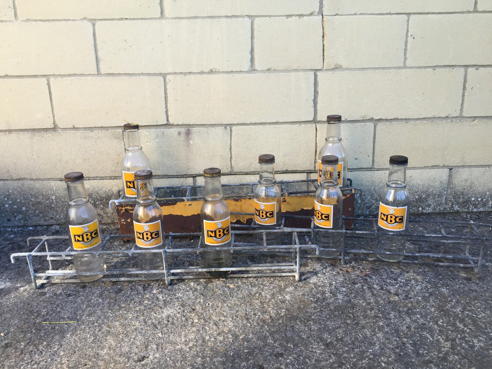 Three National Benzole Company oil bottle racks containing eight National Benzole NBC bottles.